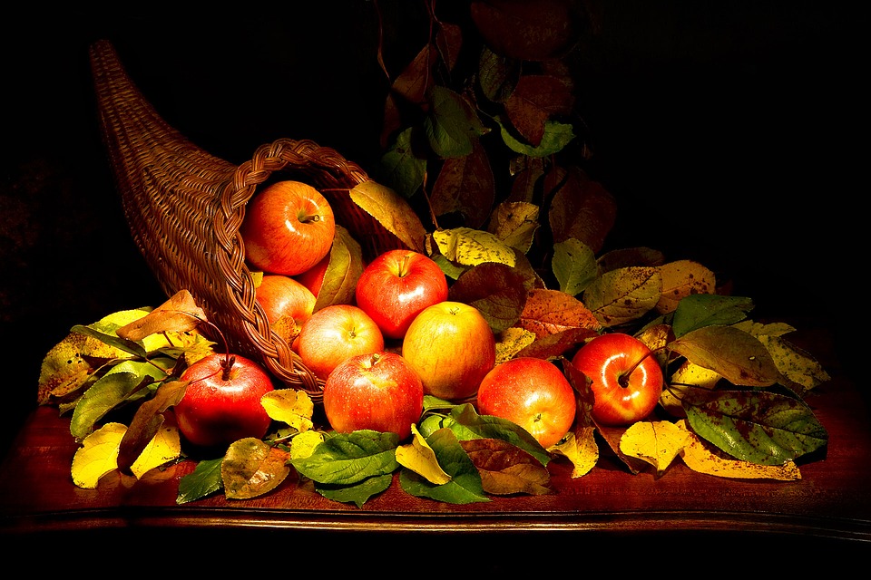 Cuerno de la abundancia sobre una mesa. Con manzanas y hojas.