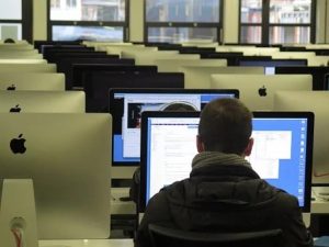 salon de capacitación con computadoras y algunas personas trabajando