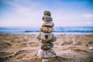 Una playa con el océano de fondo y en el primer plano unas piedras amontonadas como una torre guardando el equilibrio