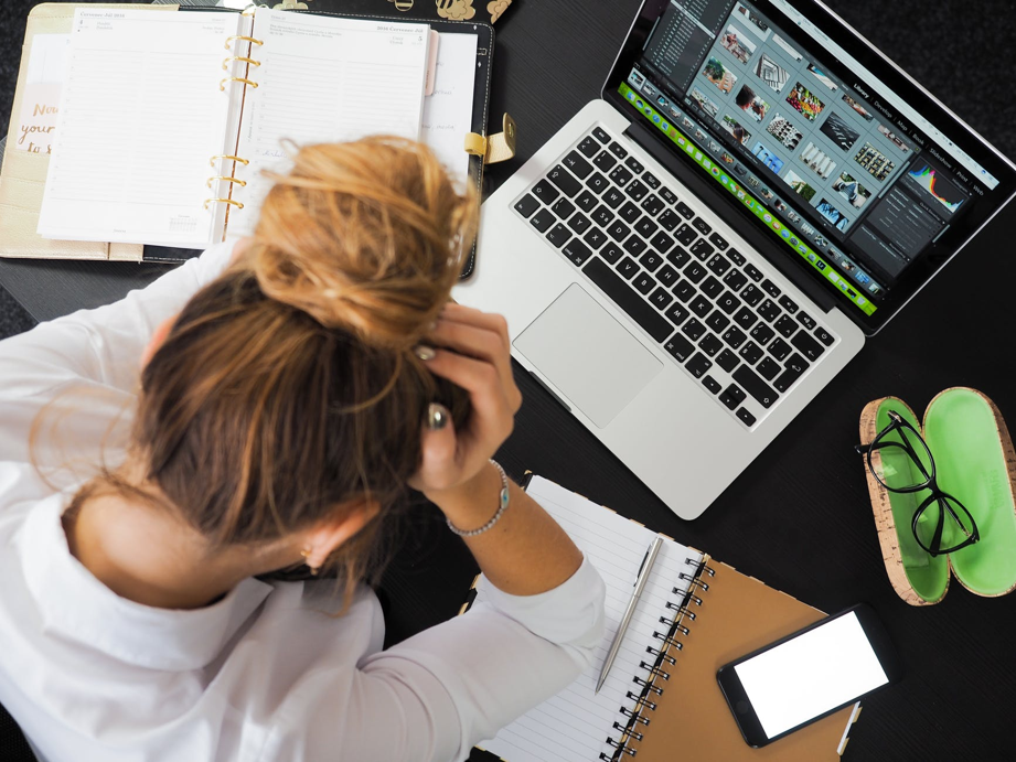 Una mujer con actitud de estar harta ante su espacio de trabajo.