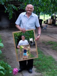 imagen de un abuelo sosteniendo una foto en la que se ve a su hijo sosteniendo una foto de su nieto.